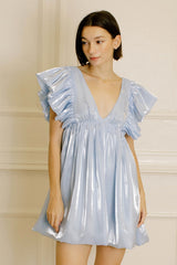 woman wearing a shiny light blue mini dress with dramatic ruffled sleeves and a deep v-neckline