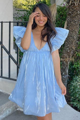 smiling woman wearing a light blue ruffled mini dress with a deep v-neck and puff sleeves