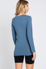 woman wearing a blue long sleeve top, viewed from the back, paired with black shorts