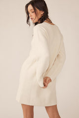 woman wearing an ivory ribbed knit sweater dress with long sleeves and a relaxed fit, shown from the back