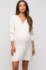 woman wearing a cream v-neck knit maternity dress and showing her baby bump
