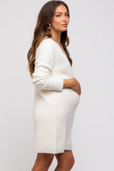 woman wearing a white ribbed maternity dress with a v-neck and holding her baby bump