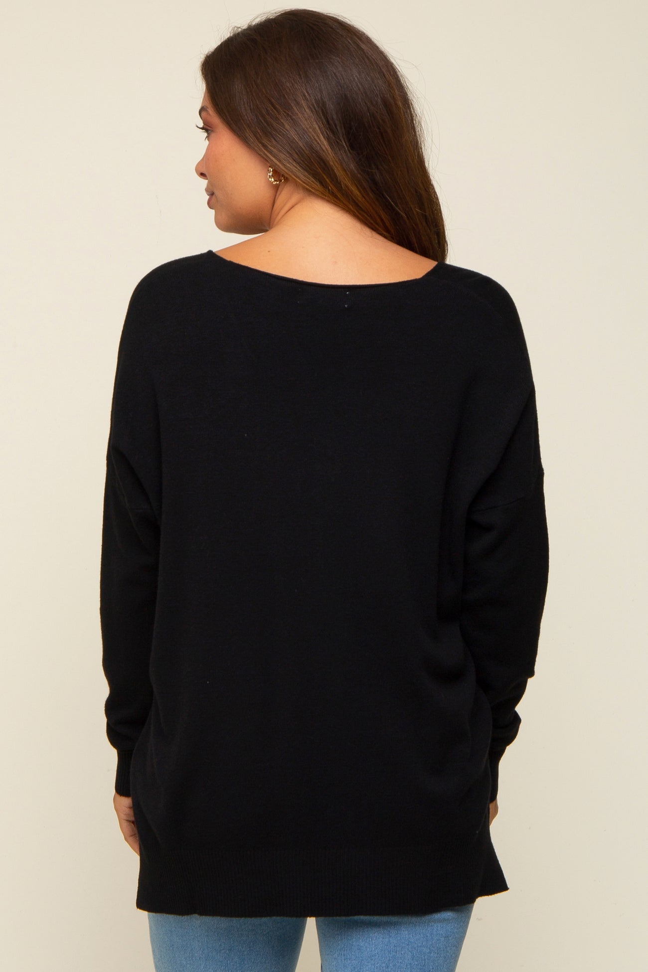 woman wearing a black oversized maternity sweater viewed from the back, with long sleeves and a loose fit