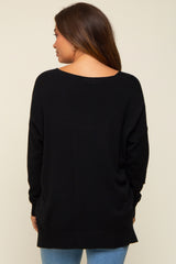 woman wearing a black oversized maternity sweater viewed from the back, with long sleeves and a loose fit