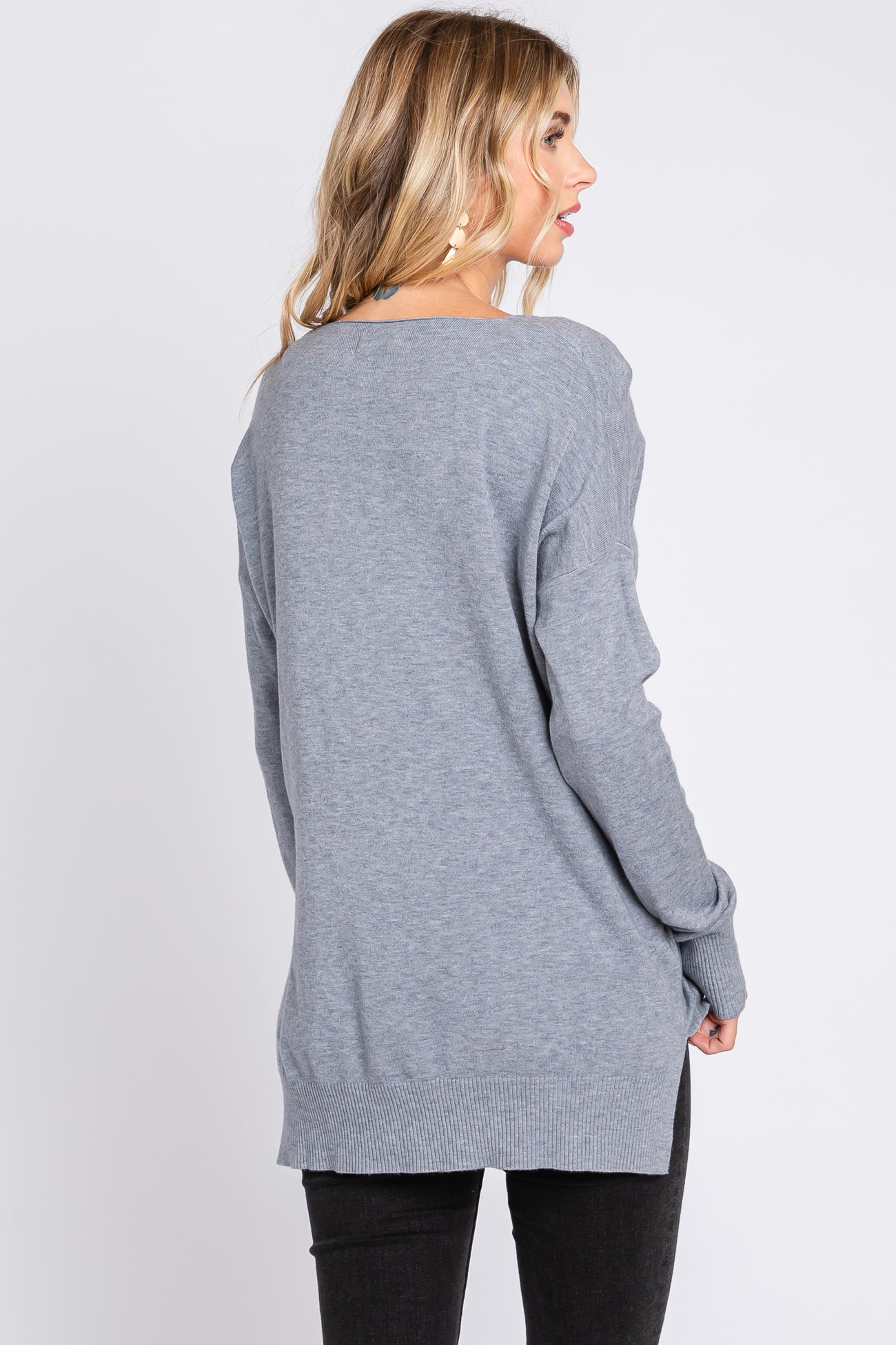 woman wearing a long gray oversized sweater with a relaxed fit and ribbed hem, viewed from the back