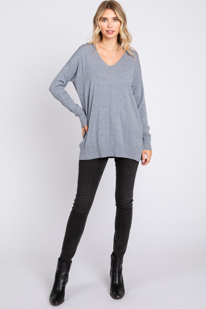 woman wearing a light gray oversized v-neck sweater paired with black skinny jeans and ankle boots