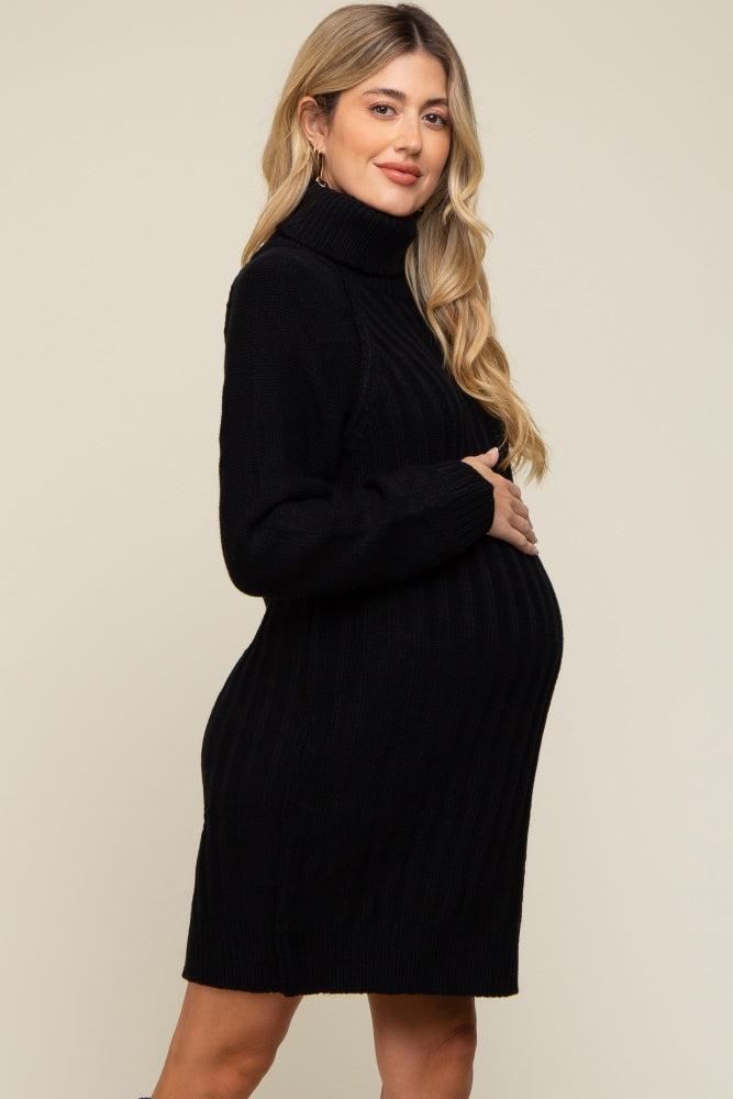 woman wearing a black ribbed maternity sweater dress, gently cradling her baby bump