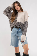 woman wearing oversized color block knit sweater and distressed denim shorts with black boots