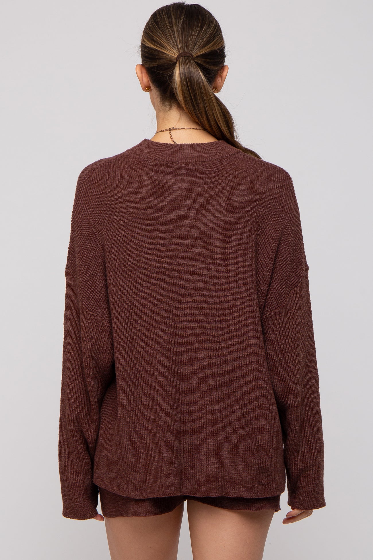 woman wearing a cozy rust long sleeve maternity sweater from the back
