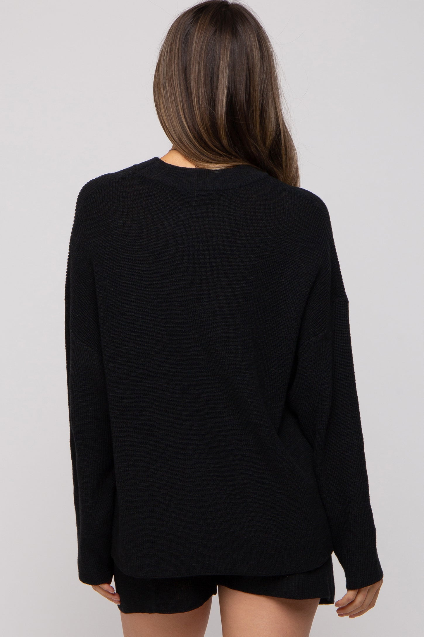 woman wearing a black oversized maternity sweater, shown from the back
