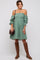 woman wearing a green off-the-shoulder smocked dress with puff sleeves and brown knee-high boots