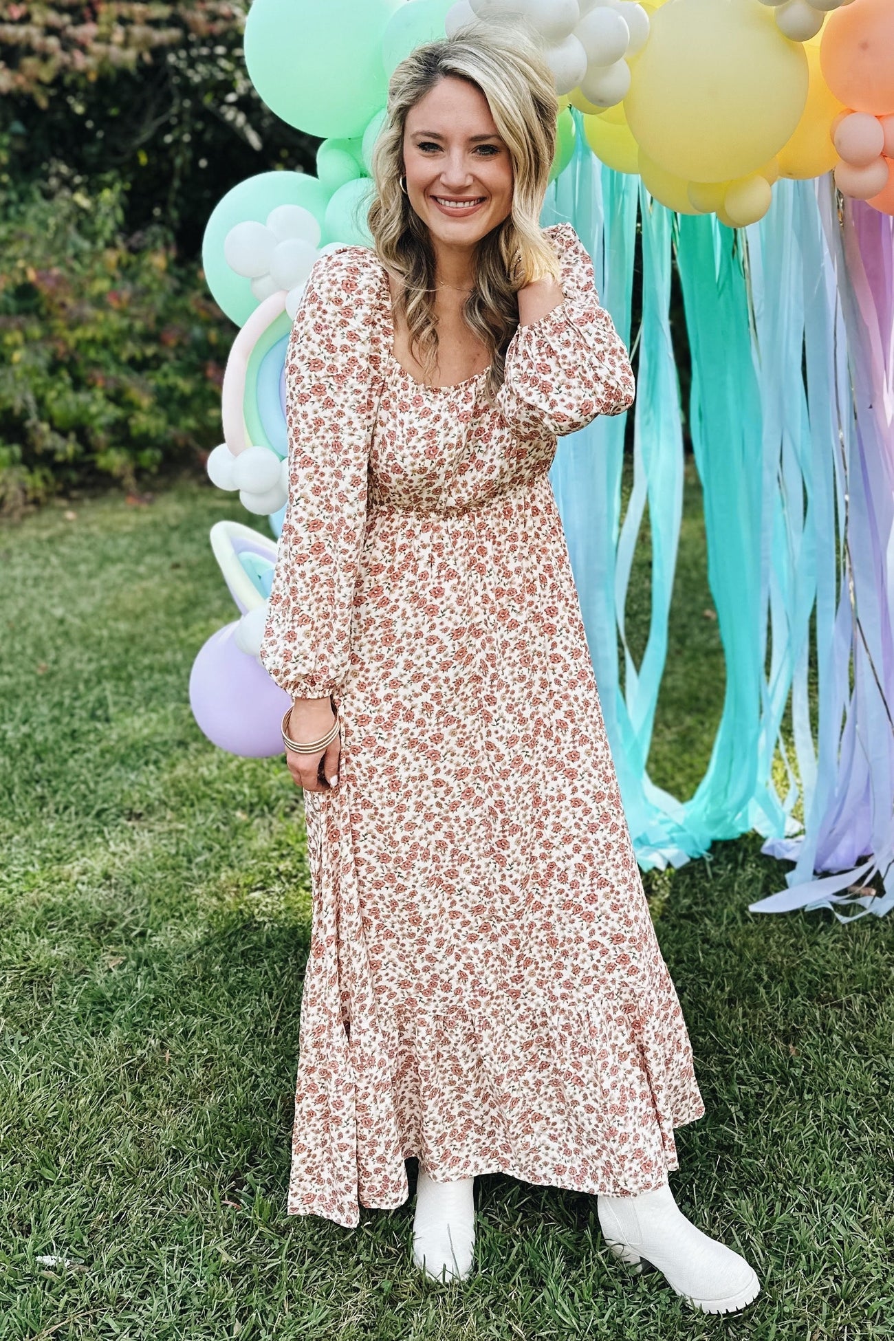 woman wearing a floral print maternity maxi dress with long sleeves and a relaxed fit, smiling outdoors with balloons in the background