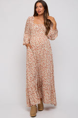 woman wearing a floral maxi dress with long sleeves and pockets, showcasing her baby bump in this maternity wear