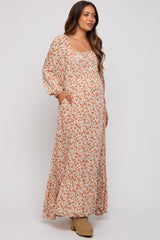 woman wearing a floral maternity maxi dress with puff sleeves and pockets, showcasing her baby bump