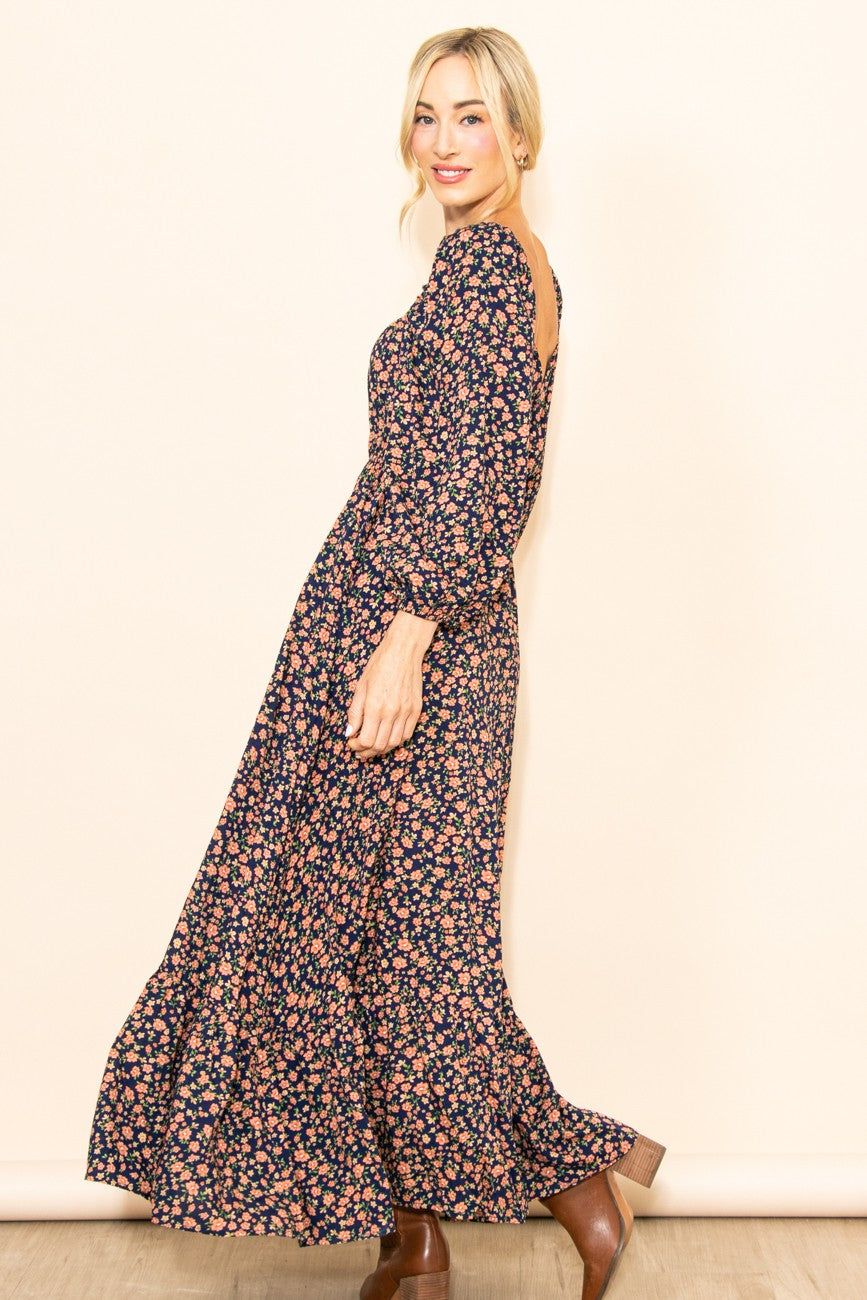 woman wearing a navy floral long sleeve maxi dress with a back cutout and smiling