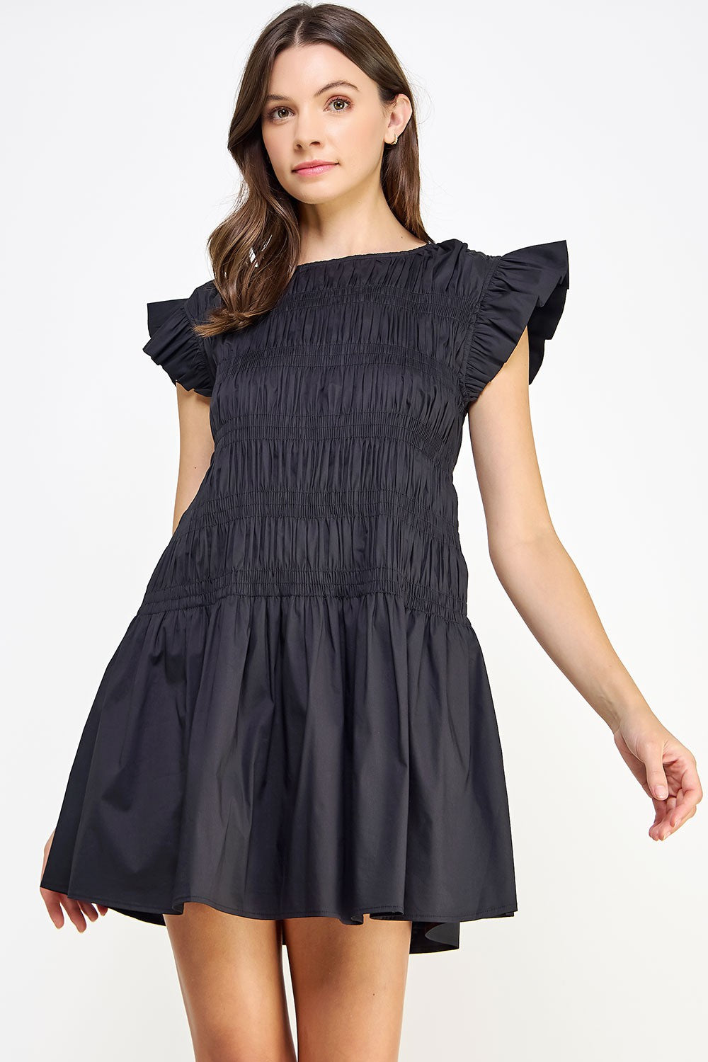 woman wearing a black smocked mini dress with ruffled cap sleeves and a flared skirt