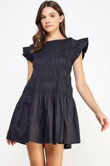 woman wearing a black smocked mini dress with ruffled cap sleeves and a flared skirt