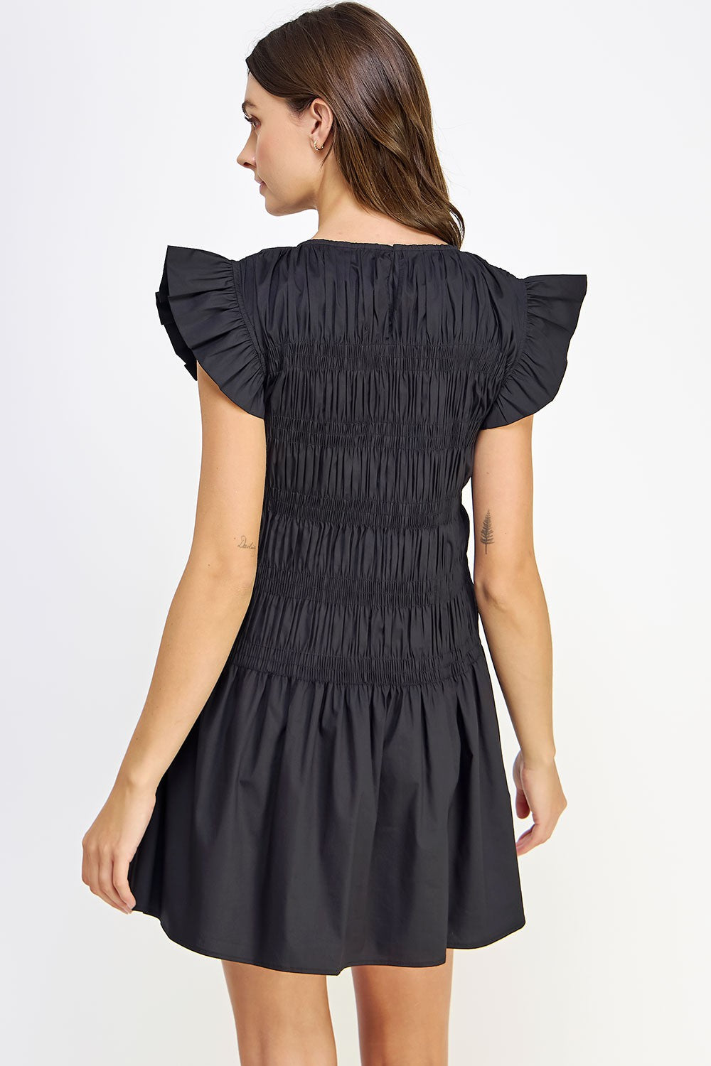 woman wearing a black smocked dress with ruffled sleeves, shown from the back