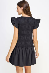 woman wearing a black smocked dress with ruffled sleeves, shown from the back