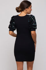 woman wearing a black ribbed maternity dress with sequined puff sleeves