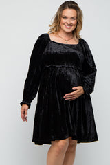 woman wearing a black velvet maternity dress with long sleeves, gently touching her baby bump