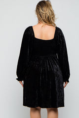 woman wearing a black velvet maternity plus dress with puff sleeves and a smocked bodice, showing her back