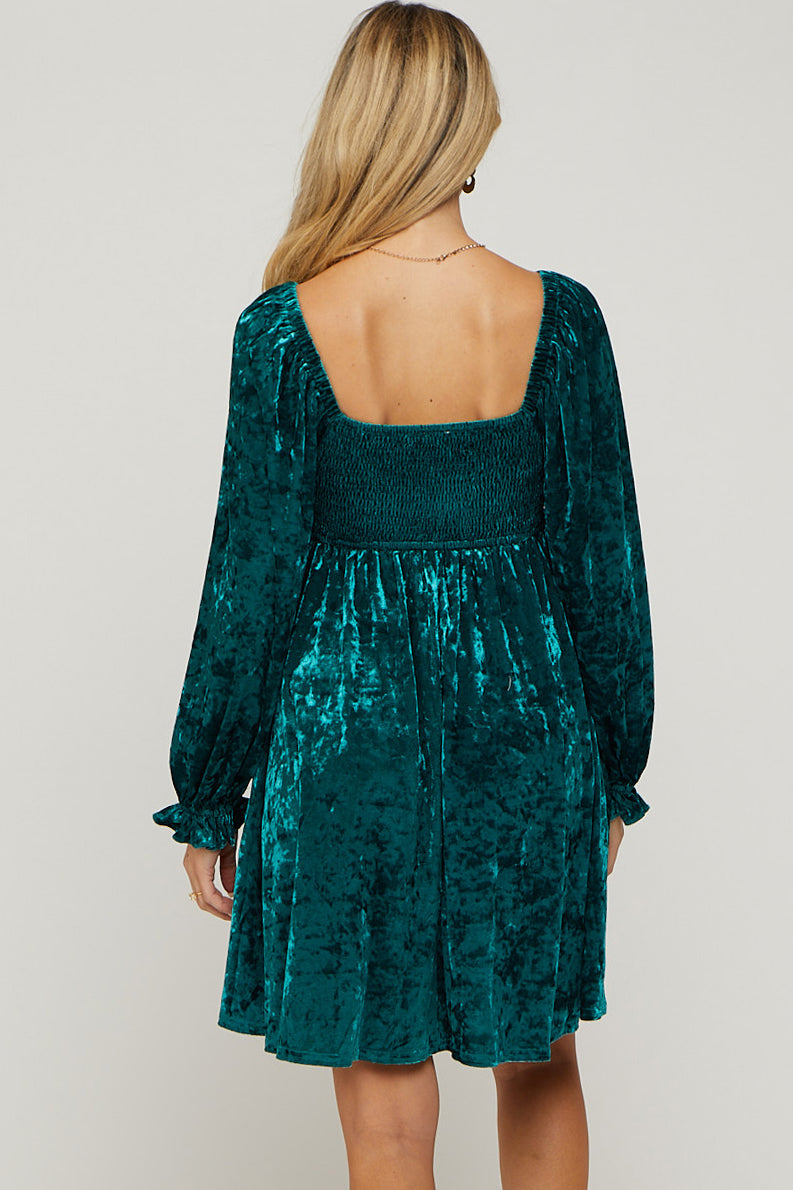 woman wearing a teal velvet maternity dress with a smocked back and long sleeves
