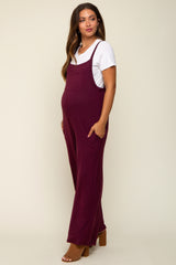 woman wearing a burgundy maternity jumpsuit with pockets and a white t-shirt, showcasing her baby bump