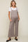 woman wearing a light brown maternity jumpsuit with pockets over a white t-shirt and showing a baby bump