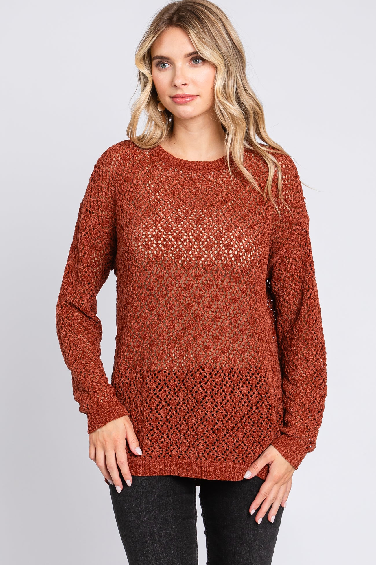 woman wearing a rust-colored open knit sweater with long sleeves and a relaxed fit