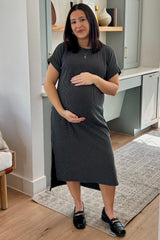 woman wearing a black and white striped maternity dress, holding her baby bump