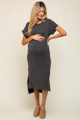 woman wearing a dark gray ribbed maternity dress, gently cradling her baby bump with a side slit detail