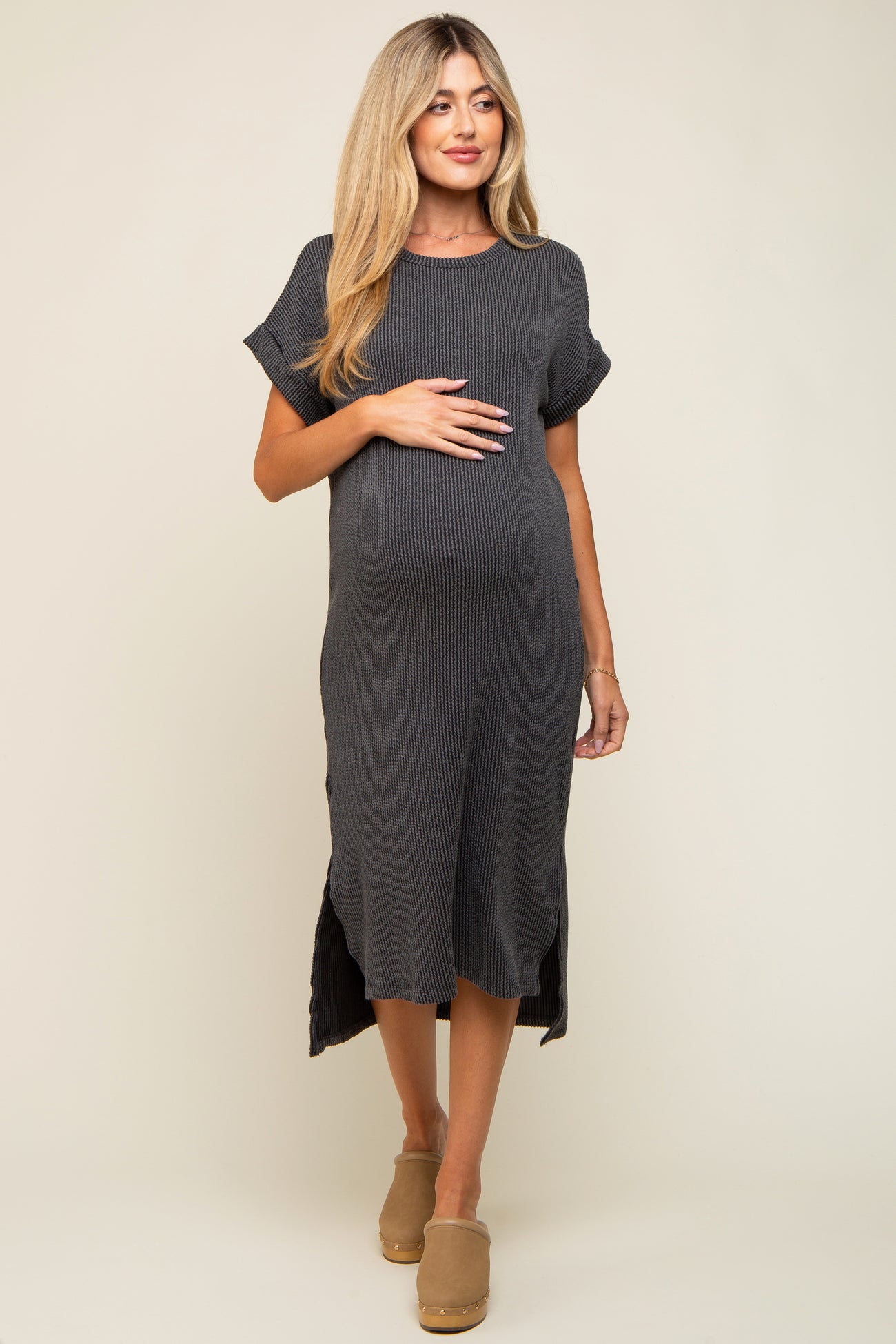 woman wearing a dark gray ribbed maternity dress with short sleeves and a side slit, highlighting her baby bump
