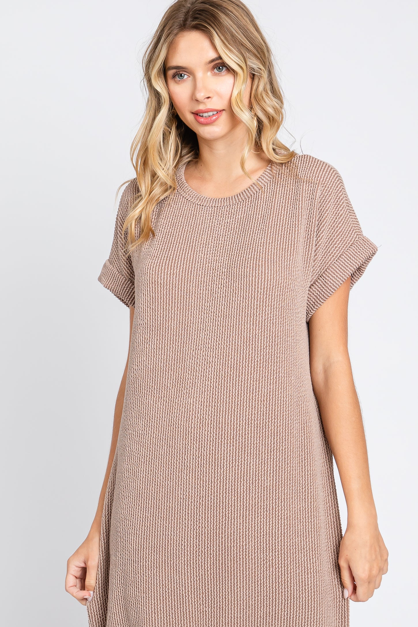 woman wearing a taupe ribbed short sleeve dress with rolled cuffs and a relaxed fit
