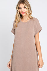 woman wearing a taupe ribbed short sleeve dress with rolled cuffs and a relaxed fit