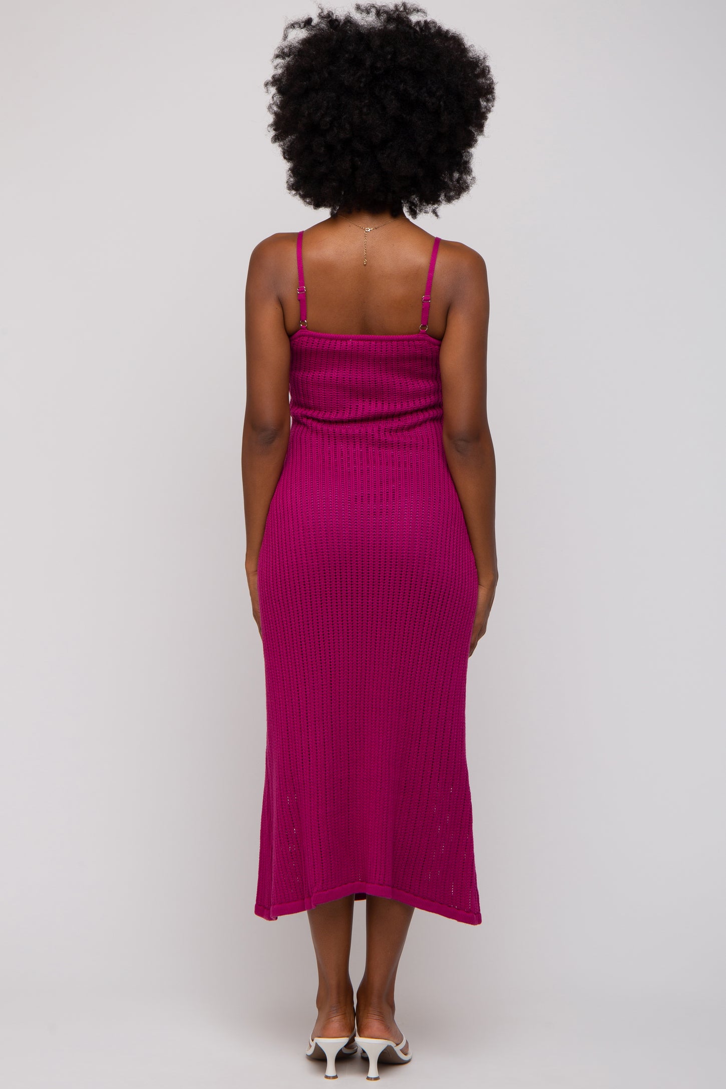 woman wearing a magenta ribbed midi dress with spaghetti straps, showing the back view