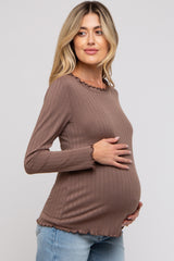 woman wearing a brown ribbed long sleeve maternity top with a scalloped neckline and holding her baby bump