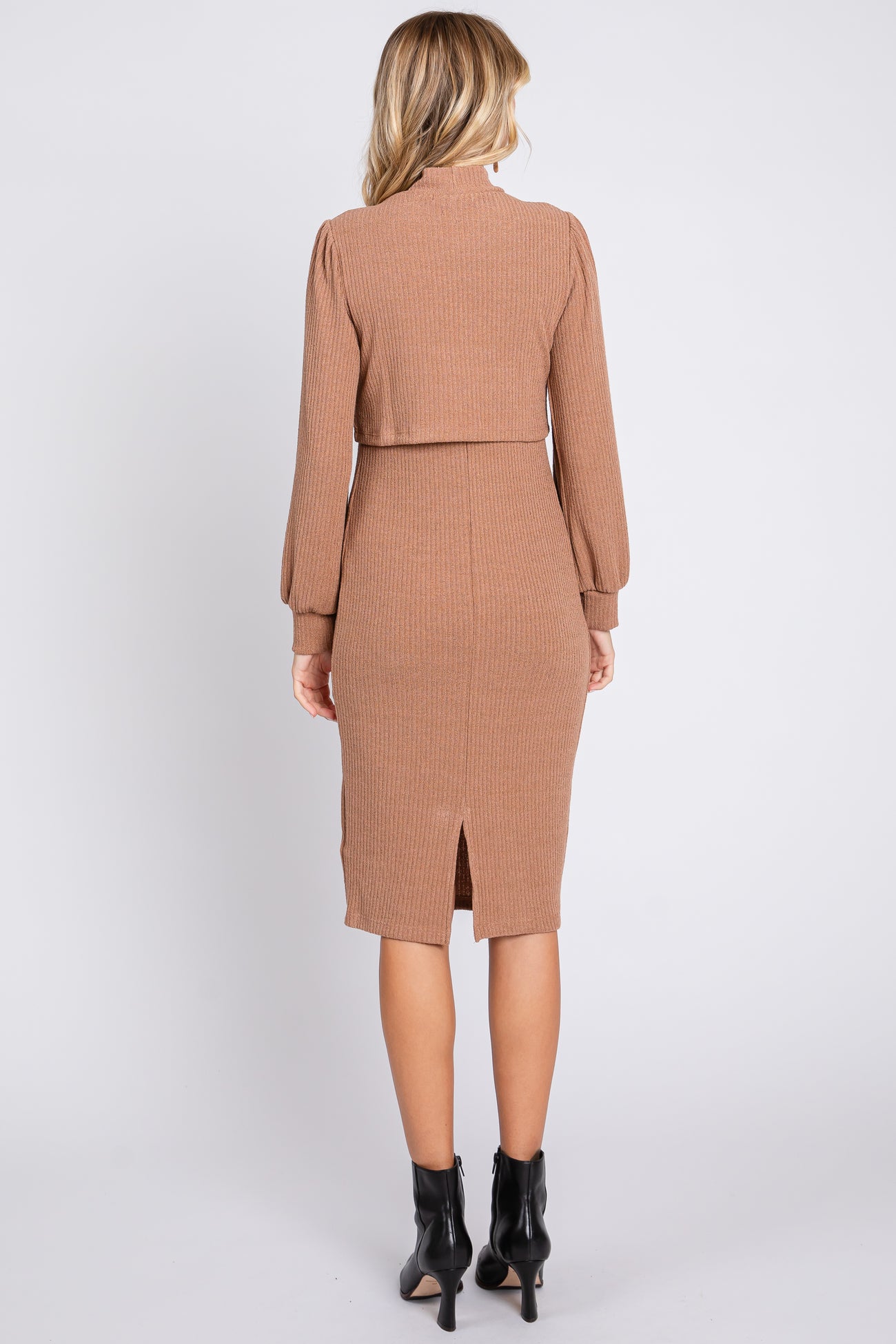 woman wearing a ribbed brown fitted dress with long sleeves and a back slit, shown from the back