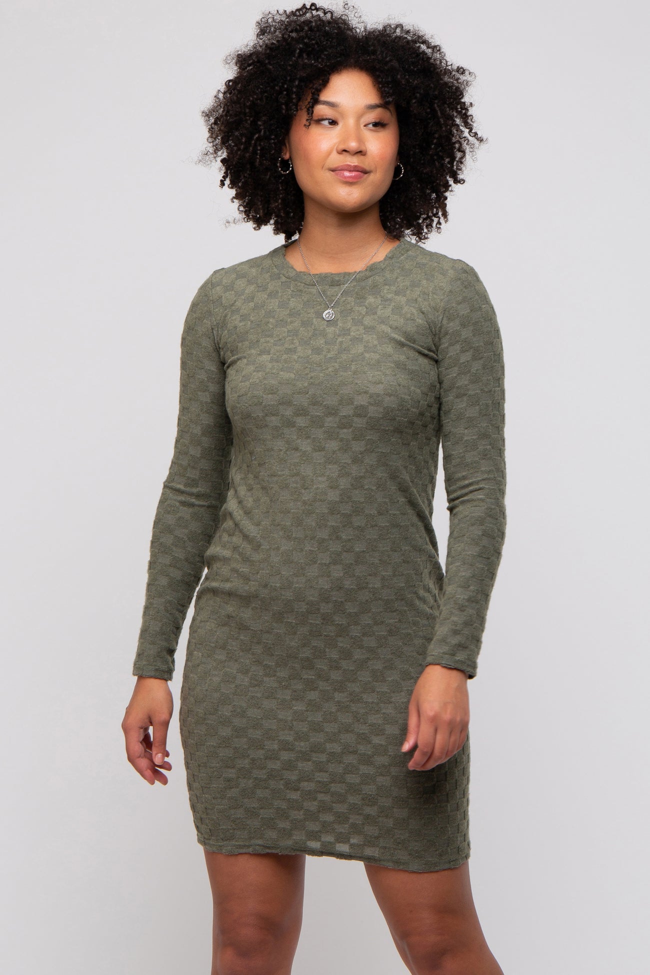 woman wearing a dark green long sleeve checkered mini dress with a fitted silhouette