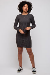 woman wearing a dark gray textured long sleeve dress and holding sunglasses, styled with black sneakers