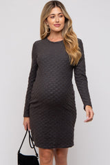woman wearing a dark gray long sleeve maternity dress with textured pattern and holding a black handbag, showing her baby bump