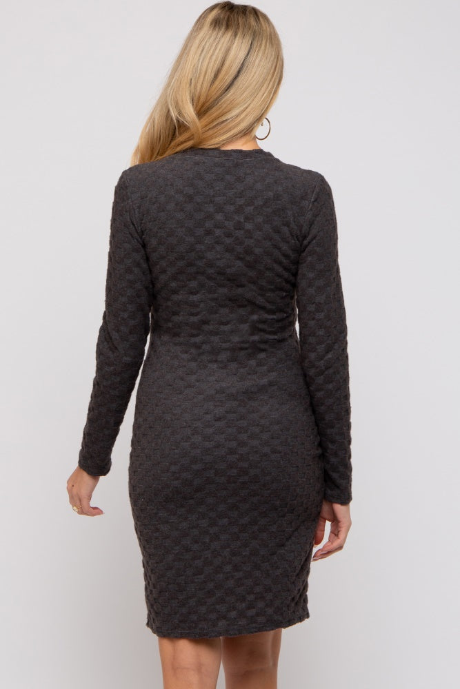 woman wearing a dark gray long sleeve maternity dress with a fitted silhouette and textured fabric