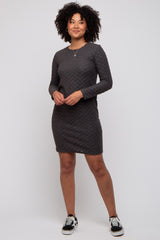 woman wearing a dark grey long sleeve fitted dress with a textured pattern and black sneakers