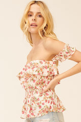 woman wearing a pink floral off-shoulder top with ruffled details and a smocked waist