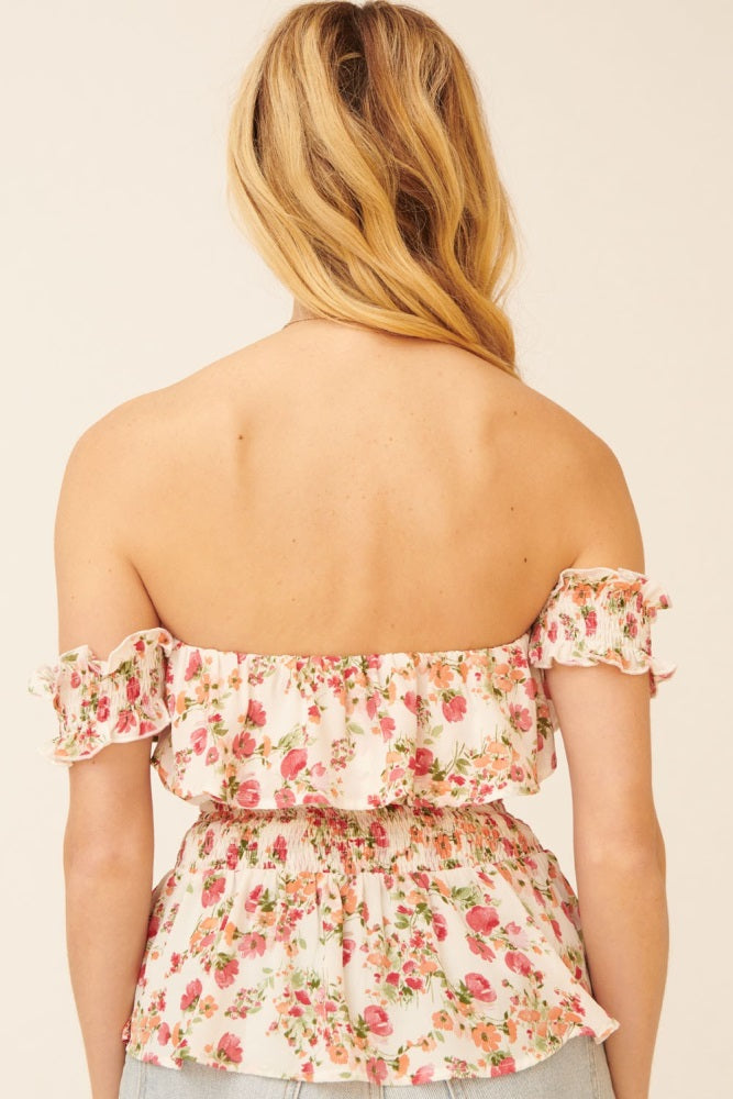 woman wearing a pink floral off-shoulder top with smocked detailing and ruffled cuffs