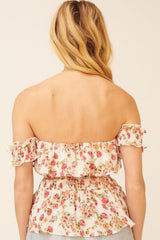 woman wearing a pink floral off-shoulder top with smocked detailing and ruffled cuffs