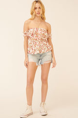 woman wearing a floral off-the-shoulder top with ruffled sleeves and distressed denim shorts