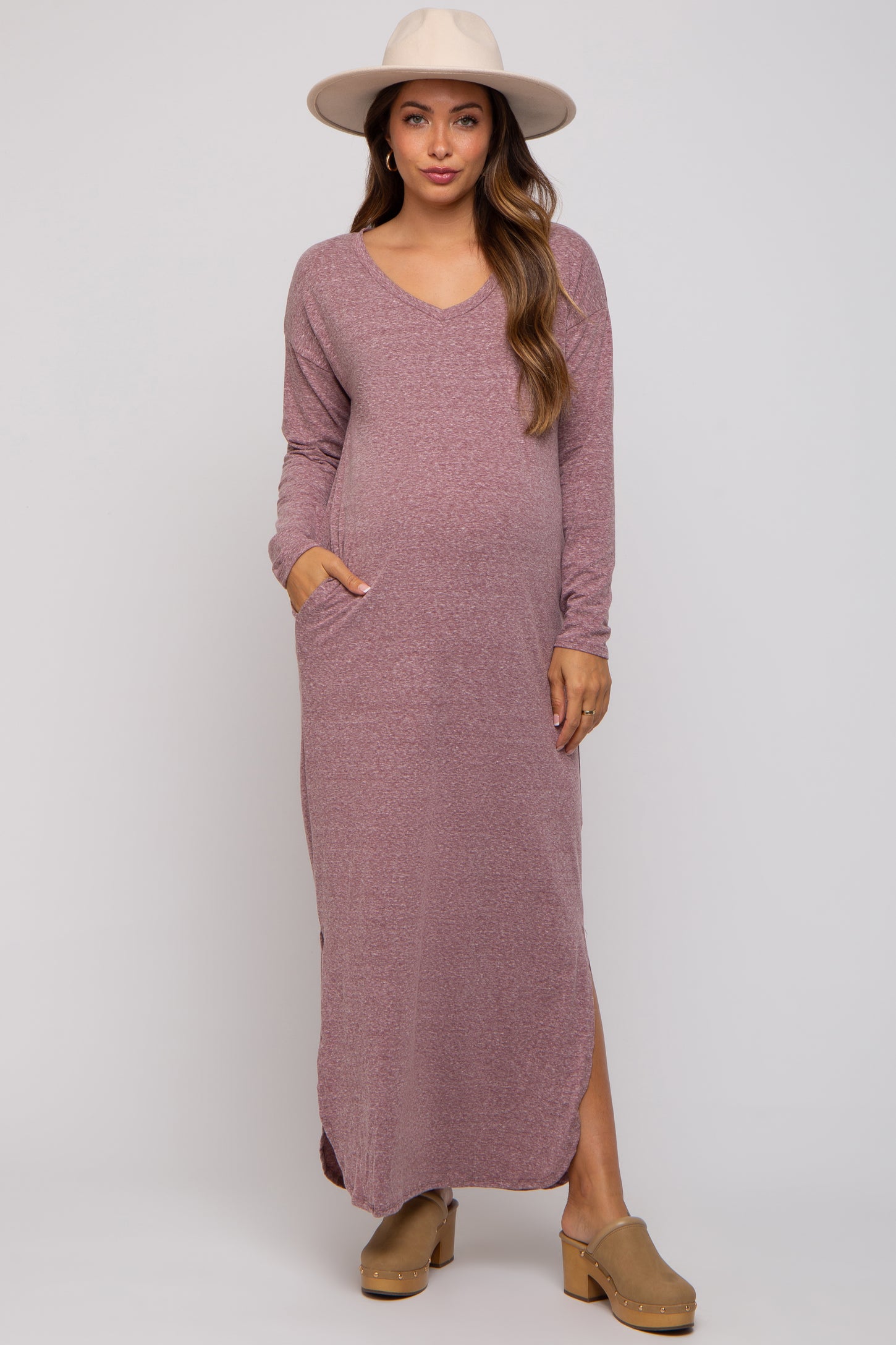 woman wearing a mauve long sleeve maternity dress with pockets and side slits, highlighting her baby bump
