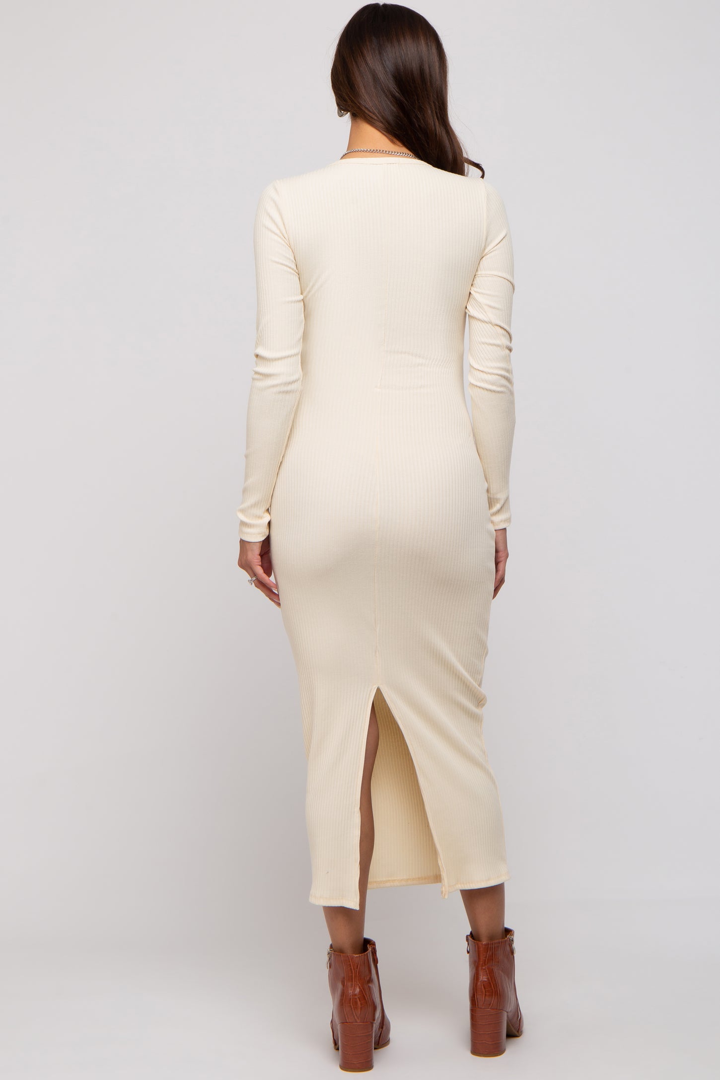 woman wearing a cream long sleeve ribbed maternity dress with a slit at the back