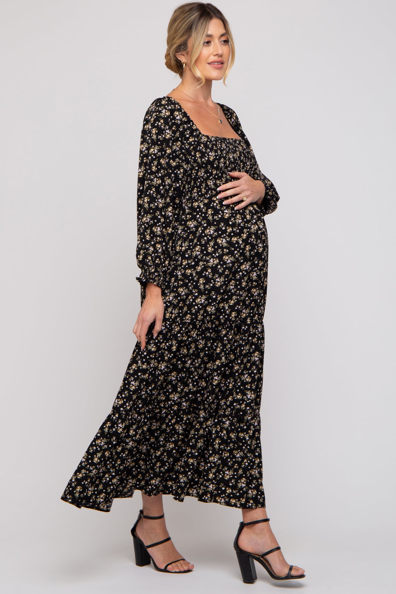 woman wearing a black floral long sleeve maternity dress and holding her baby bump